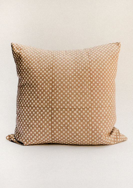 A brown throw pillow with contrast polka dot pattern.