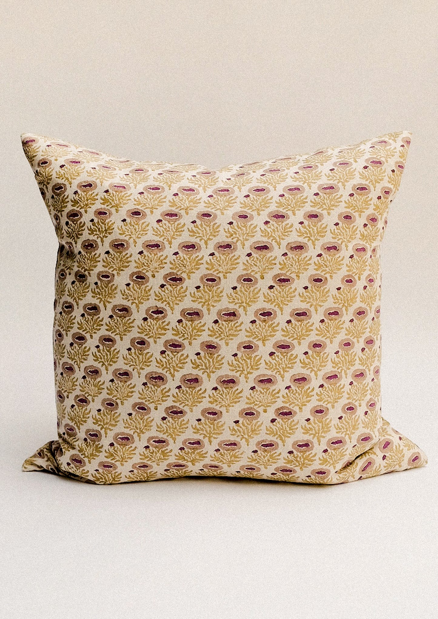 A block printed throw pillow with chartreuse and pink floral pattern.