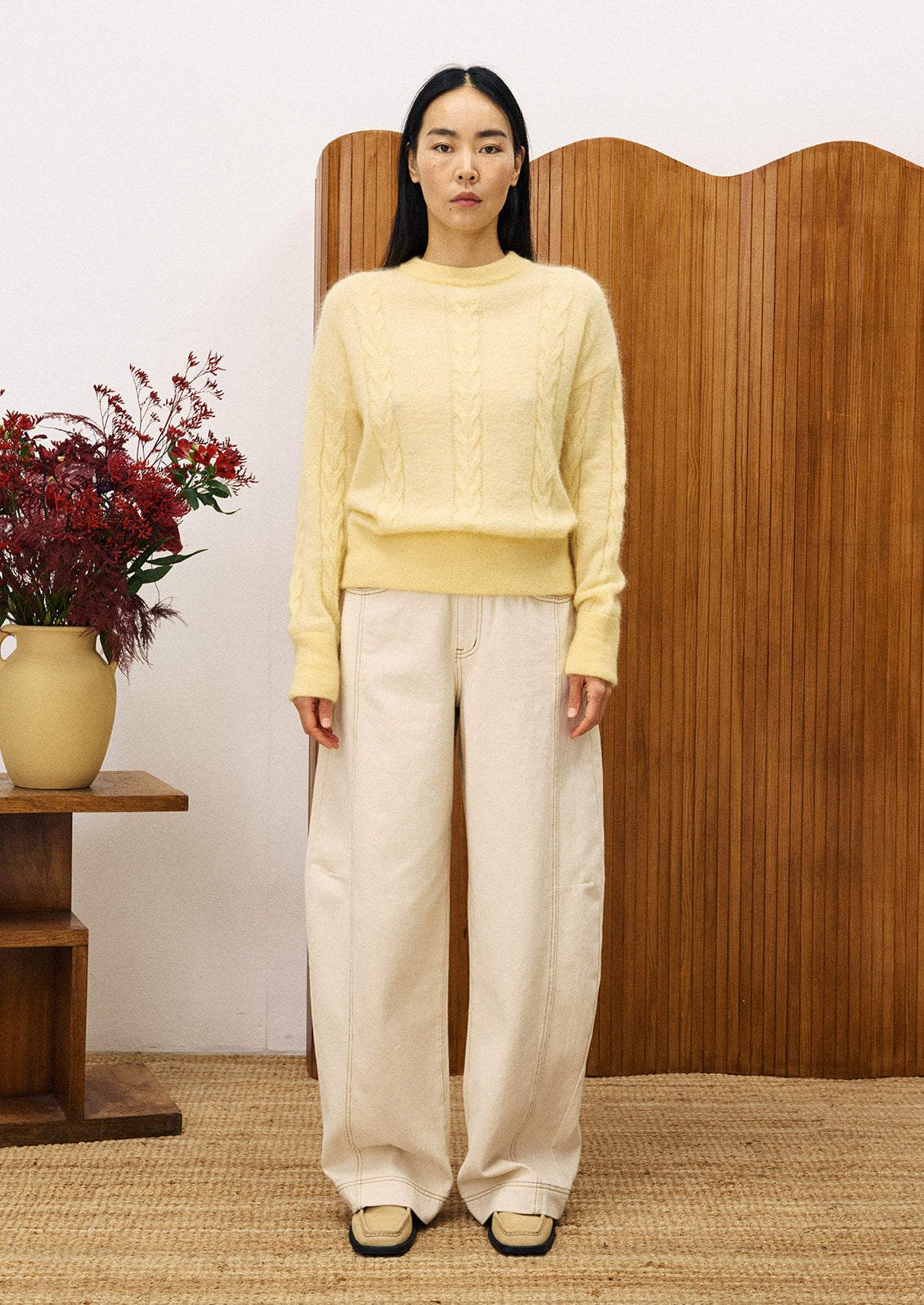 Woman wearing a light yellow cable knit sweater.