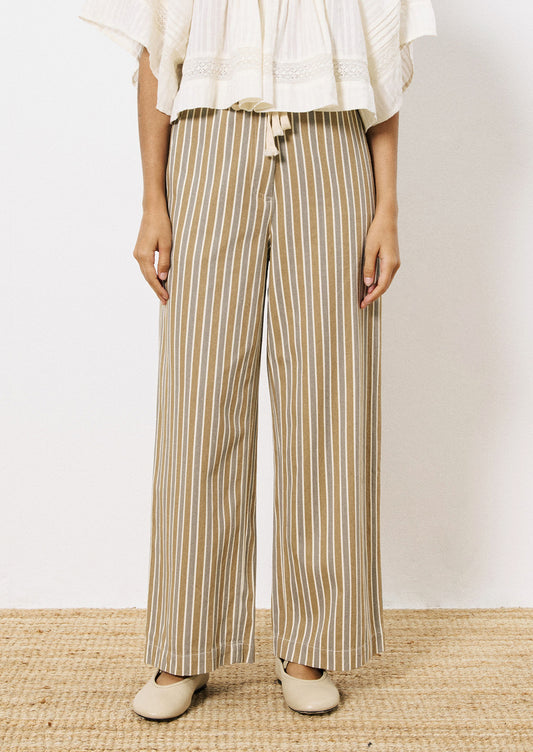 A person wearing a pair of wide leg pants in grey and brown vertical stripe pattern.