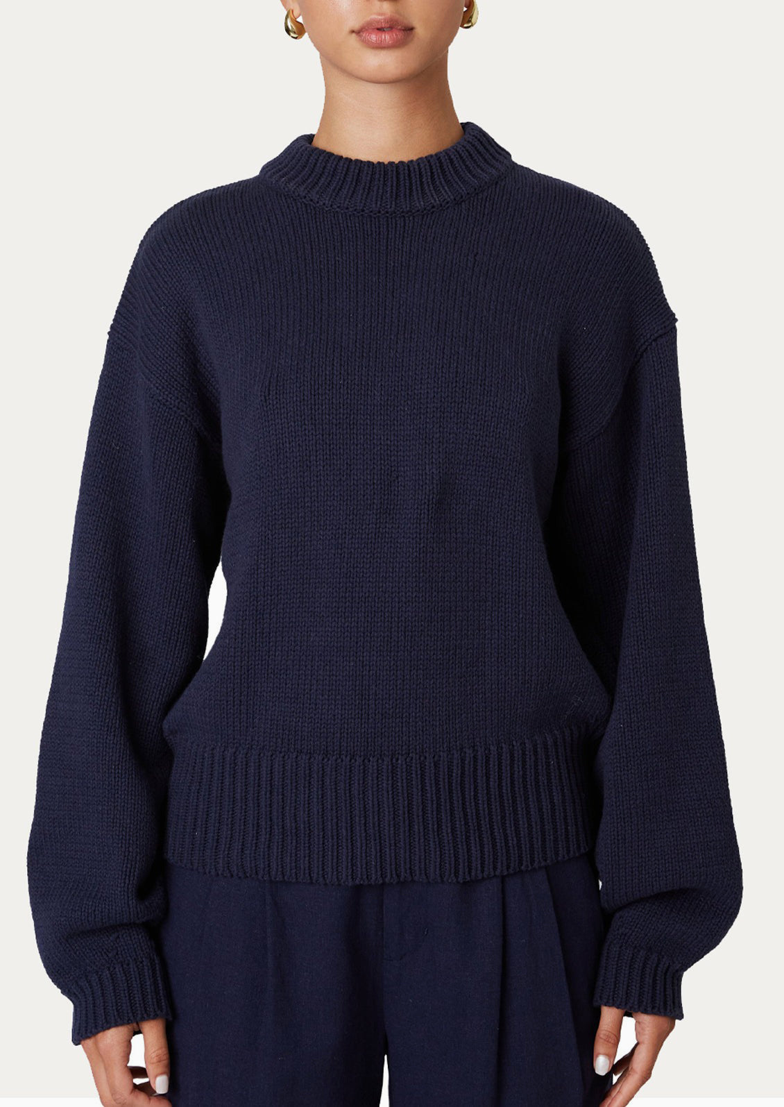 A woman wearing a crewneck sweater in navy.