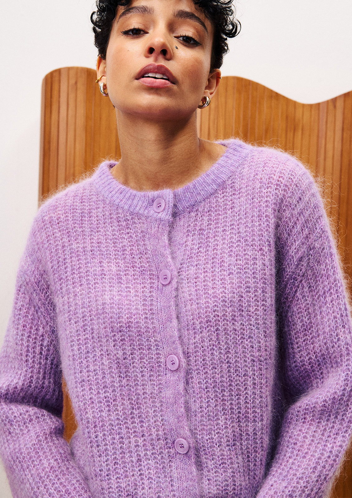 A woman wearing a cardigan sweater in medium purple color.