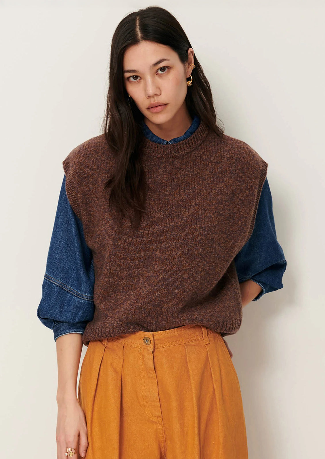 Woman wearing a brown knitted vest over a blue shirt.