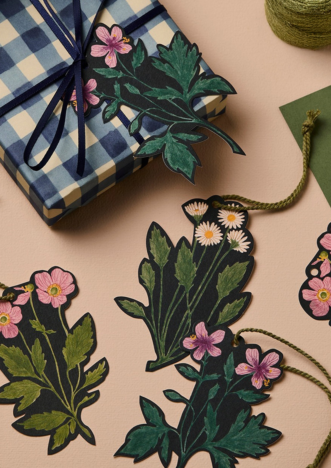 Floral gift tags and a wrapped present on a beige surface