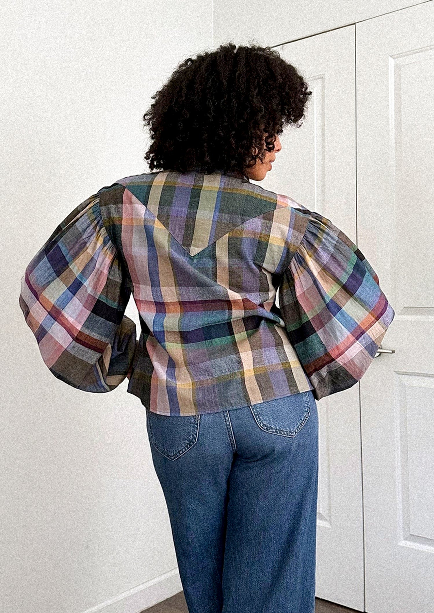 A person wearing a plaid print blouse with blouson sleeves.