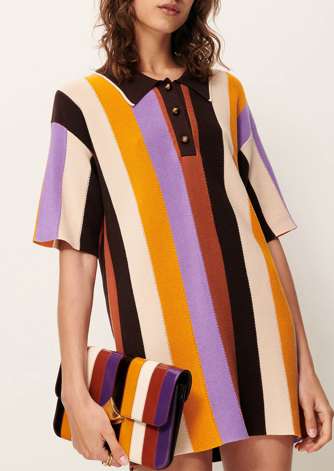 A woman wearing a colorful striped polo dress with short sleeves.
