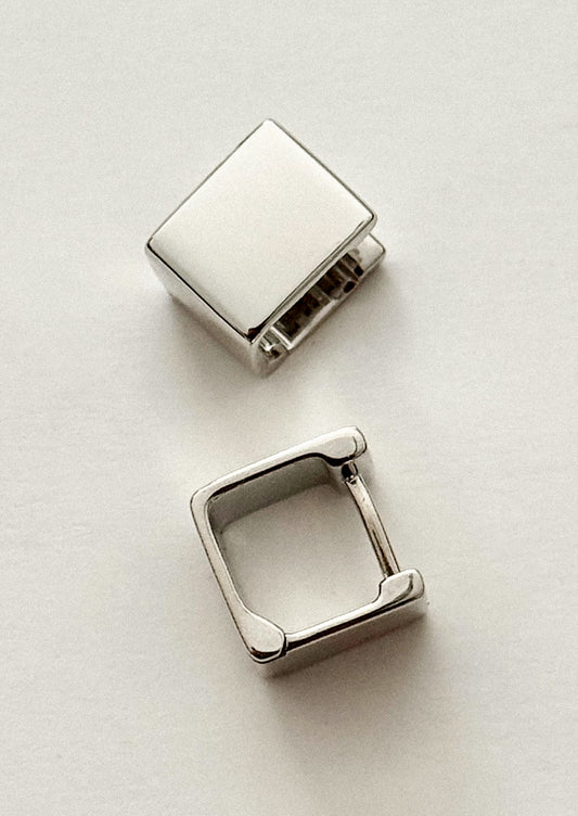 Two silver square-shaped earrings on a light gray background