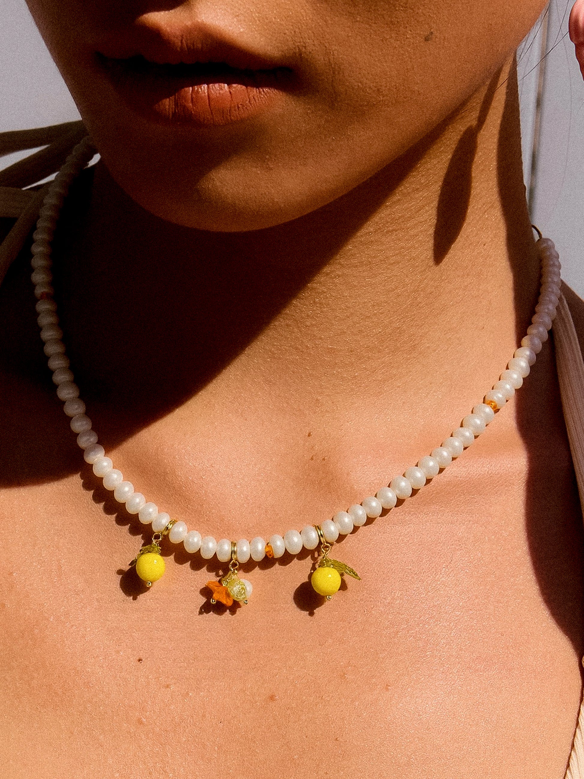 A beaded pearl necklace with lemon charms.