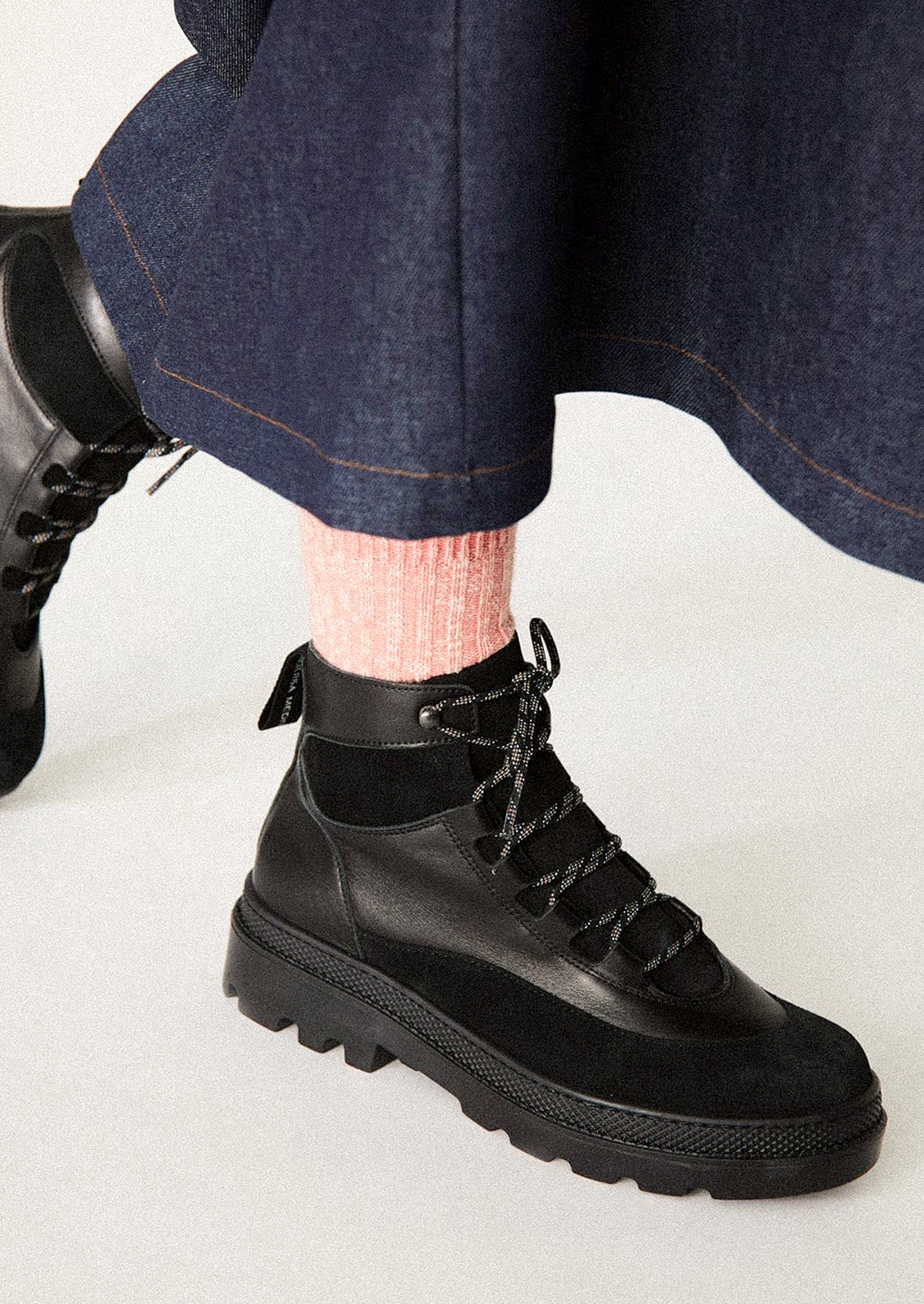 Person wearing black boots with a white background