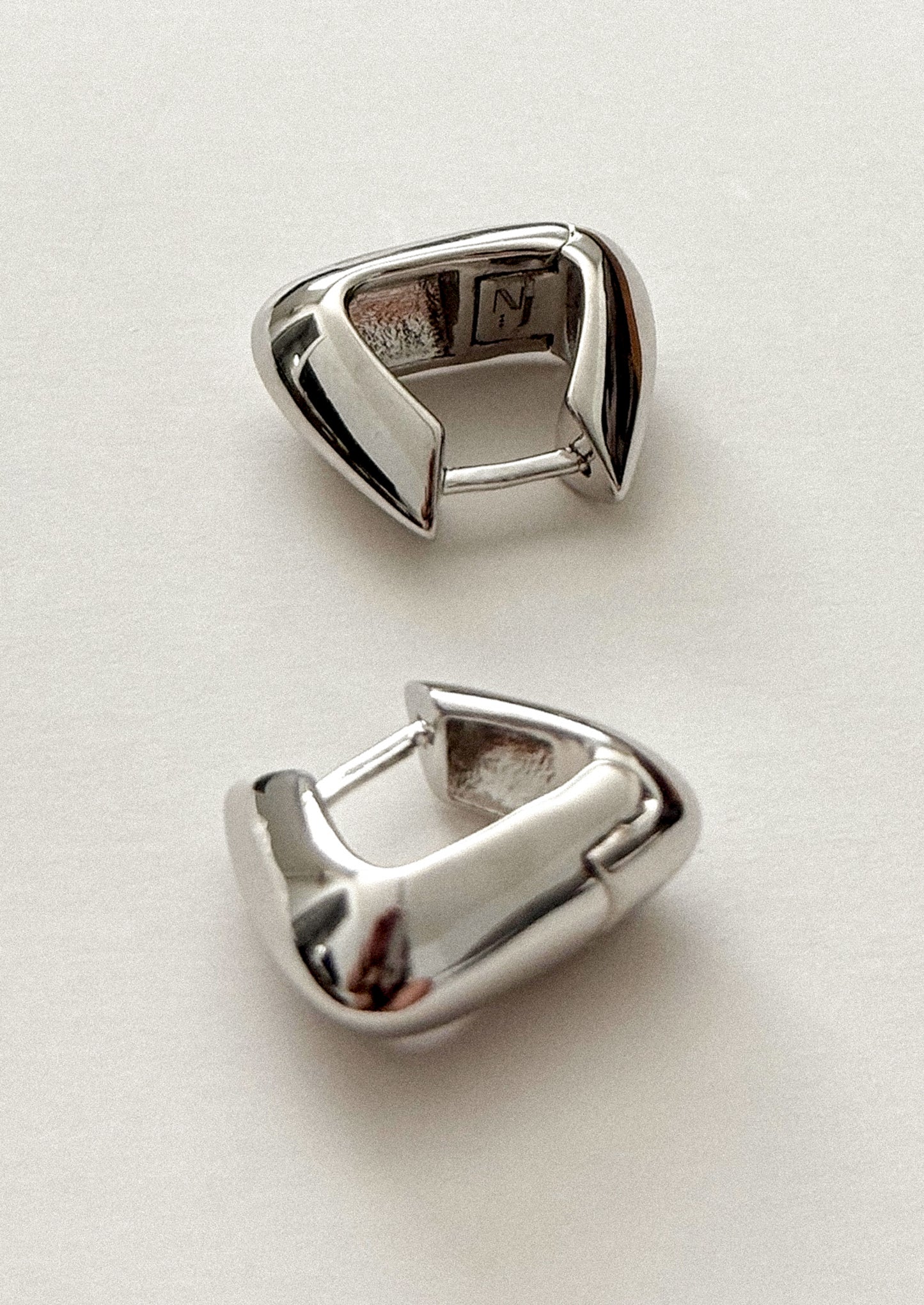 Pair of silver hoop earrings on a light gray background