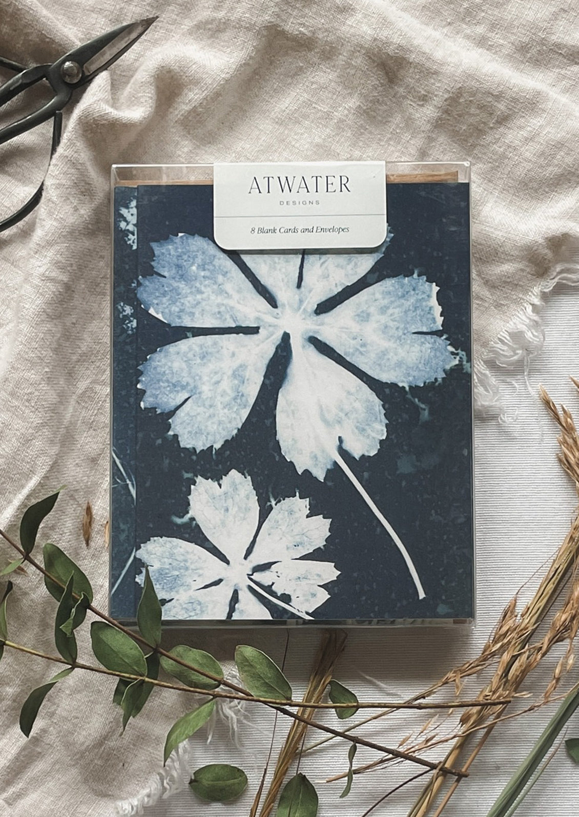 Card set with floral design on a textured surface with scissors and leaves.