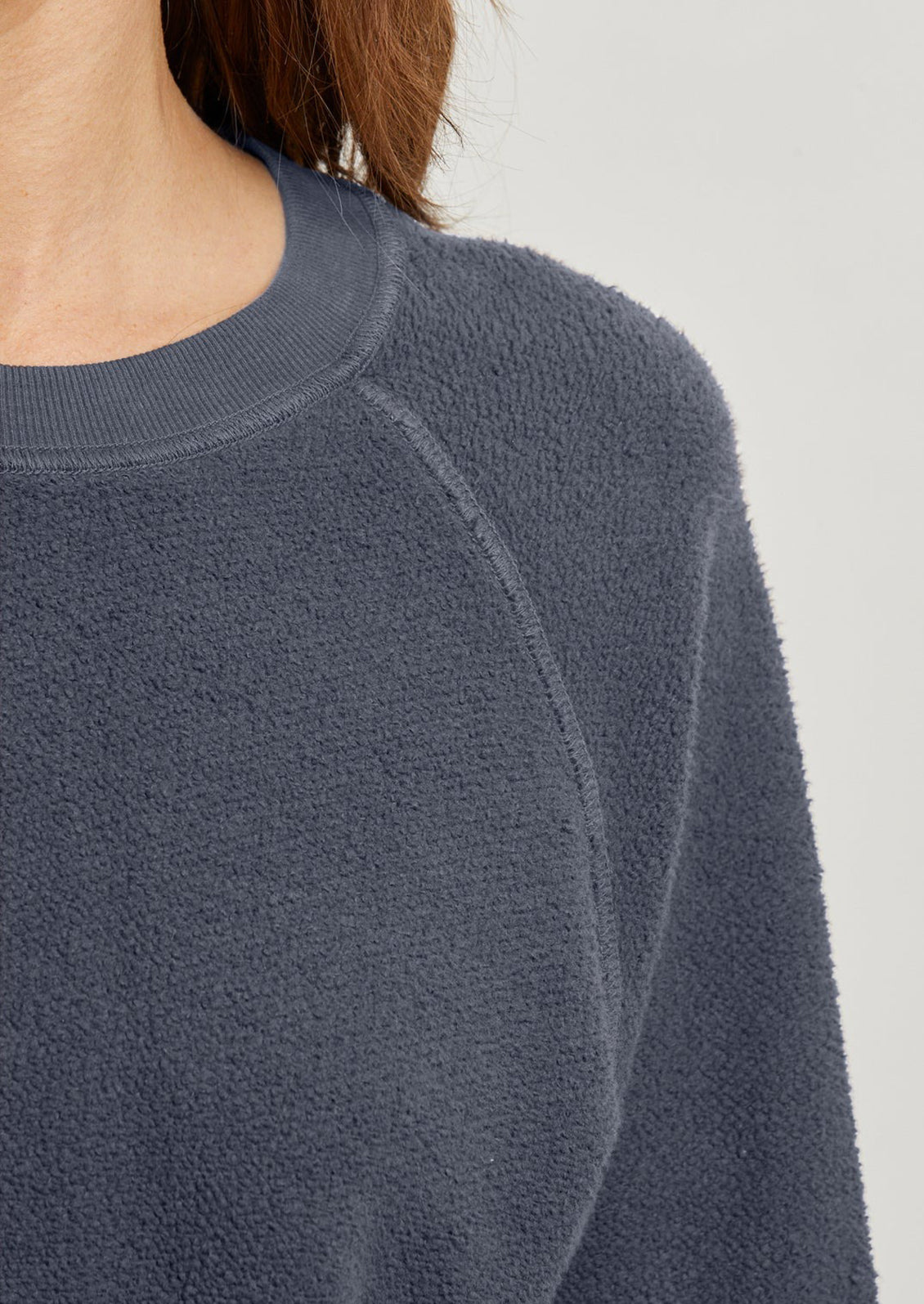 A woman wearing a reverse fleece sweatshirt in blue-grey.