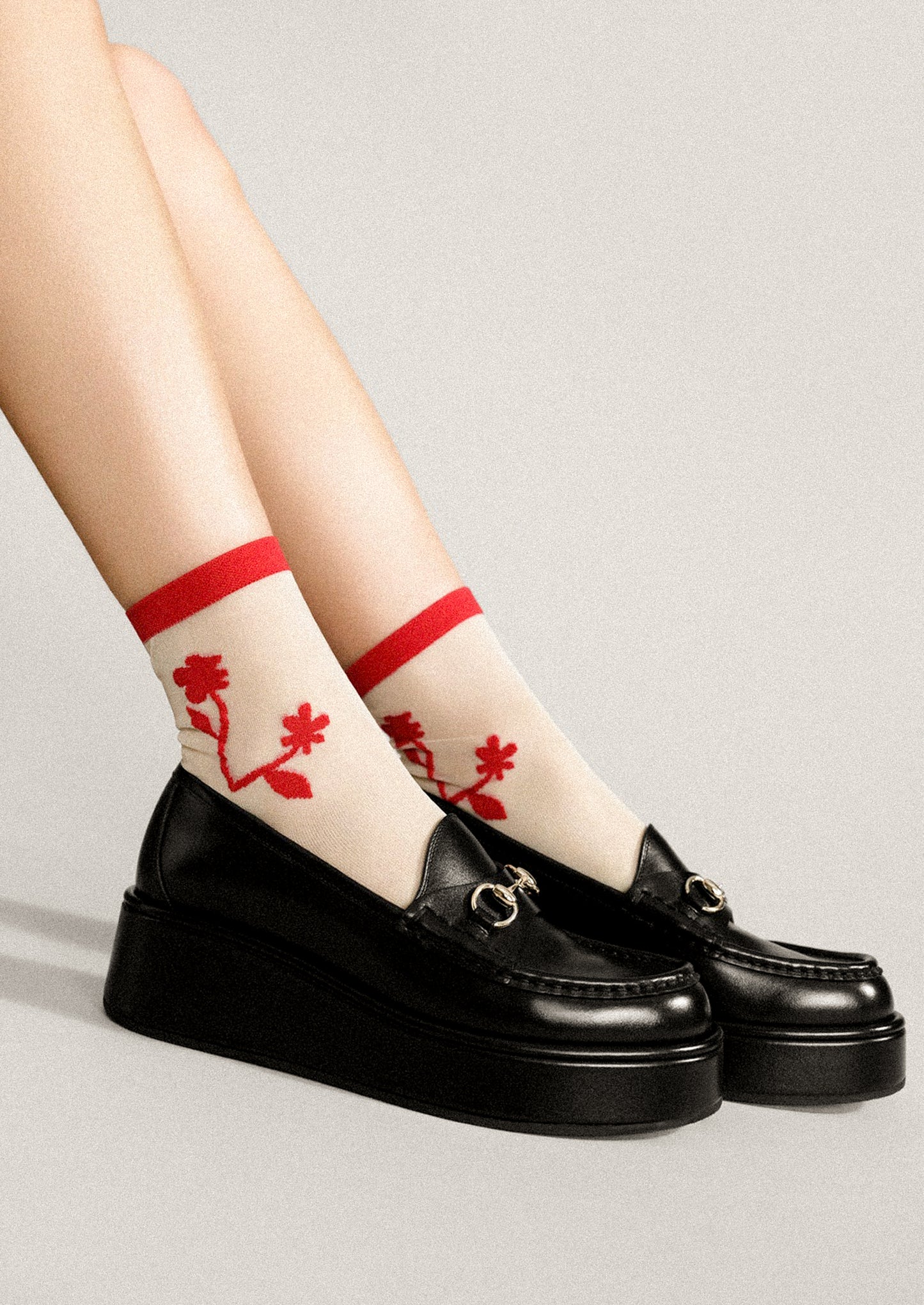 A pair of sheer nylon socks with red floral pattern.