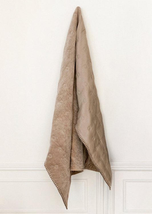 Beige blanket draped over a white wall