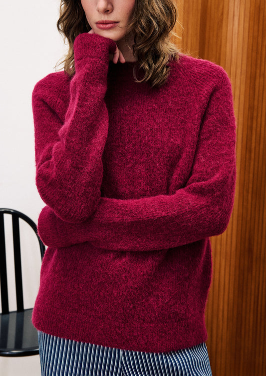 A woman wearing a knit sweater in vibrant burgundy color.