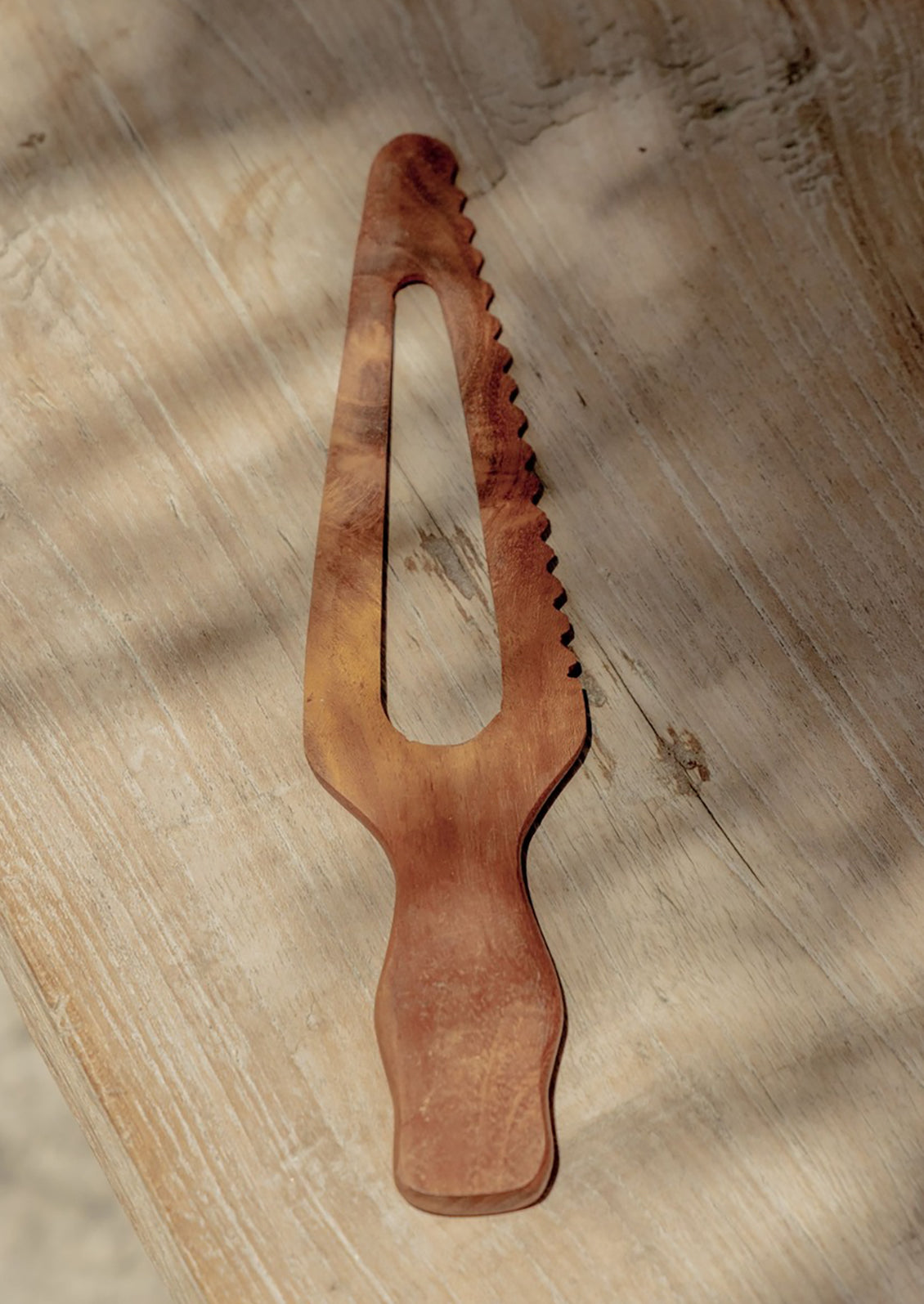 Wooden tool with a serrated design on a wooden surface