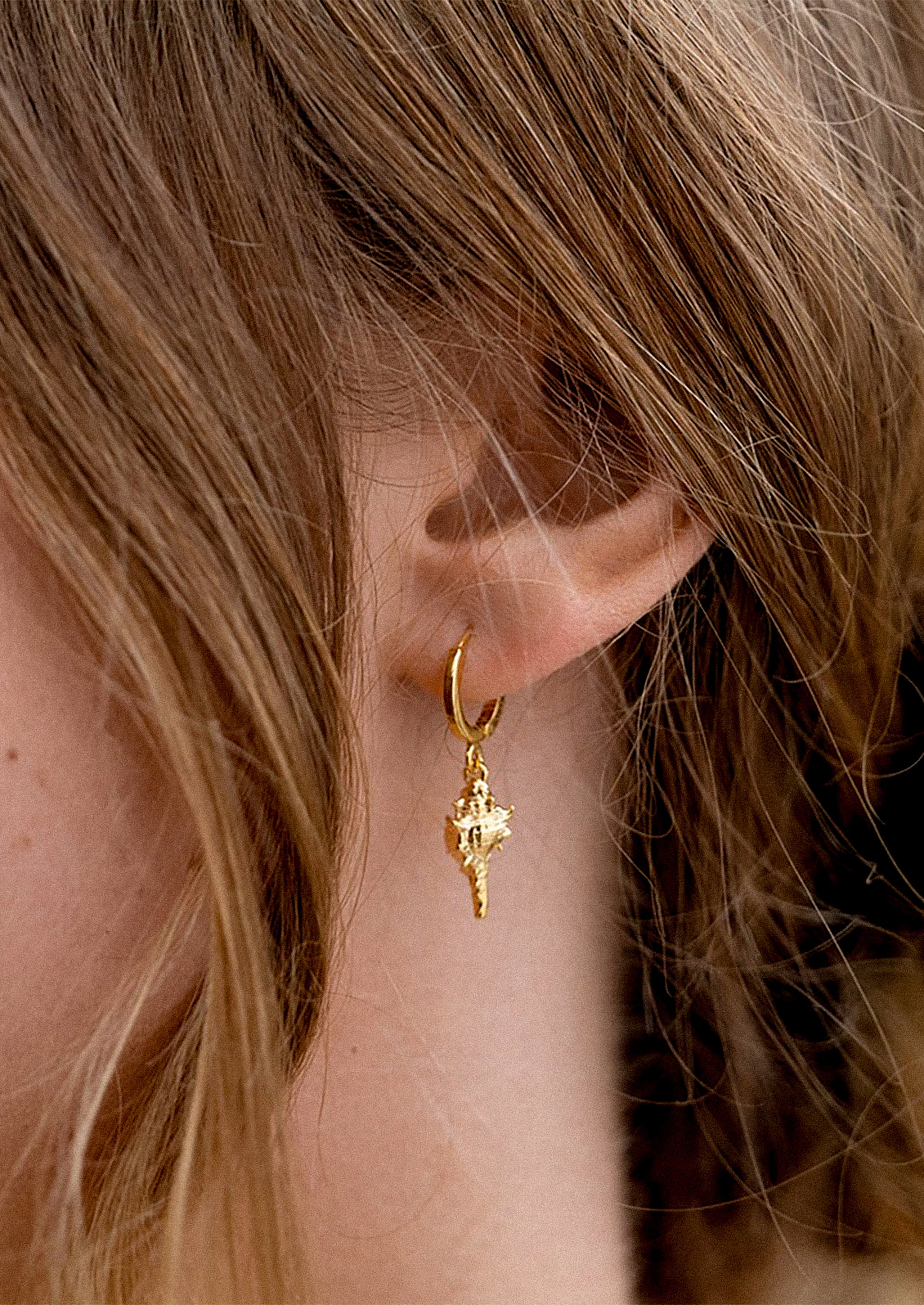 A person wearing shell earrings.