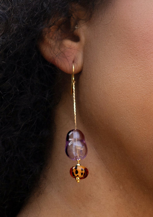 Earring with purple and orange beads worn by a person with dark hair.
