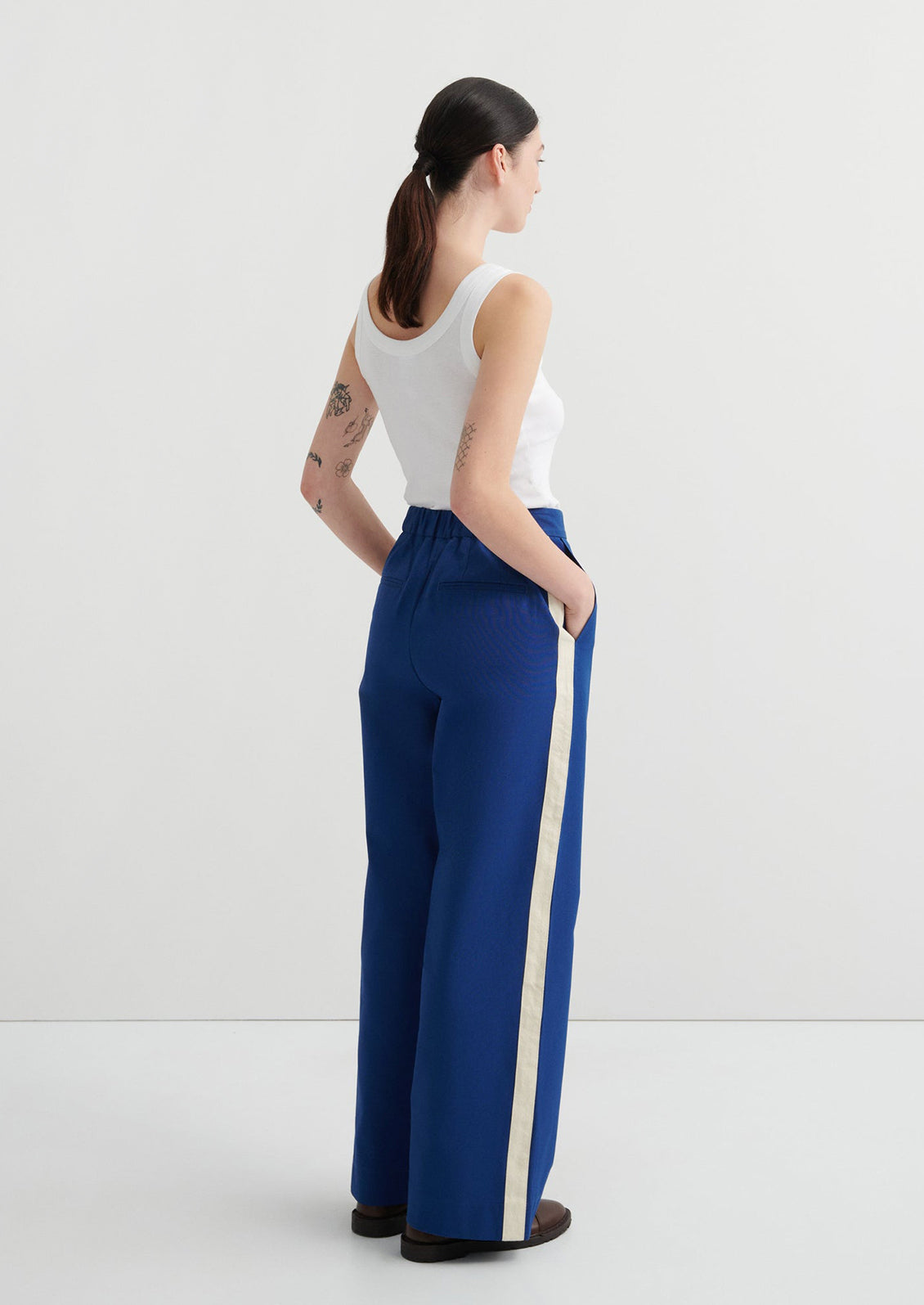 Woman wearing blue pants with a white stripe on a white background