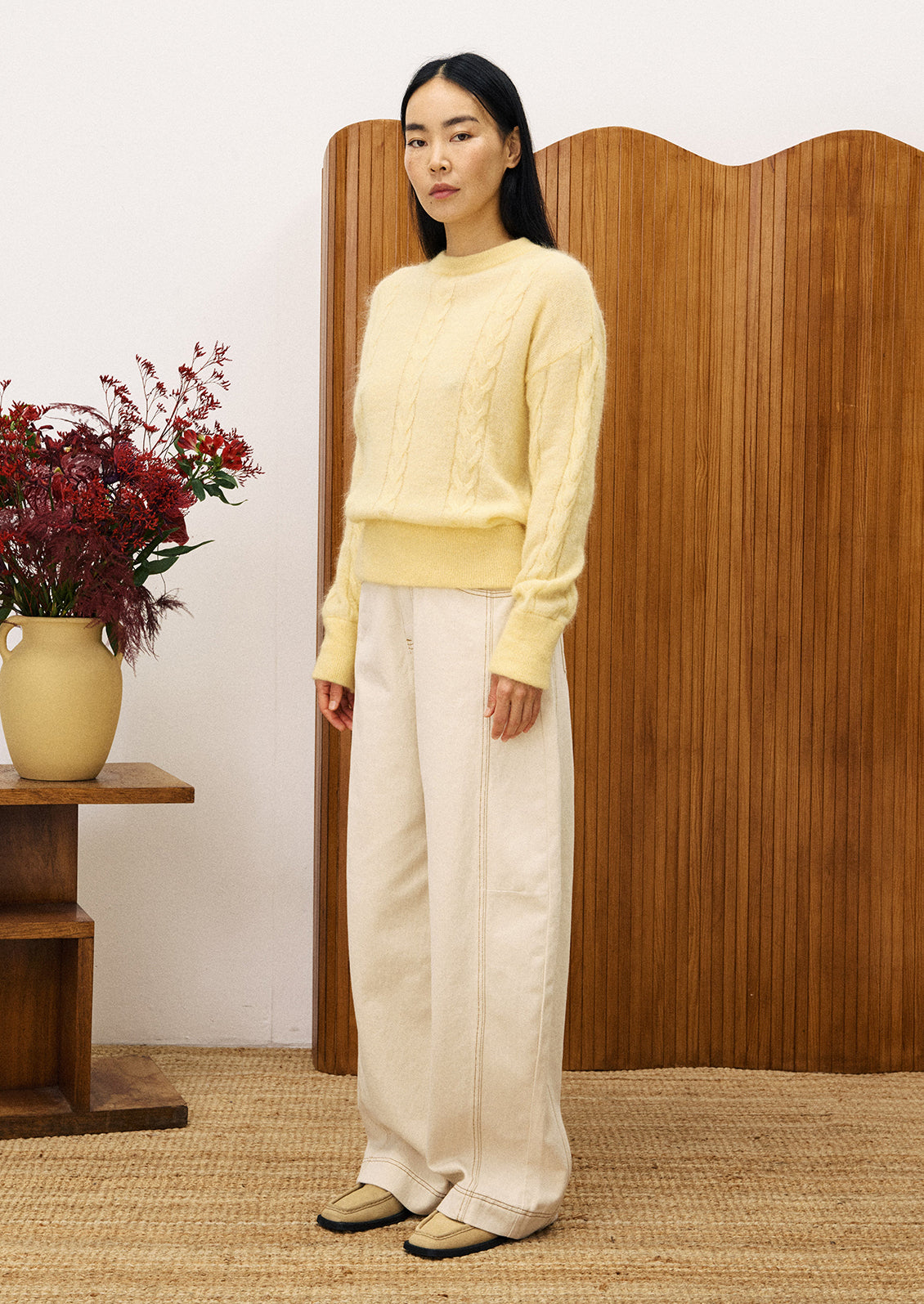 Woman wearing a light yellow cable knit sweater.