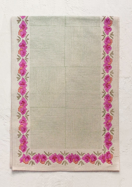 A block printed table runner with green striped pattern and pink floral border.