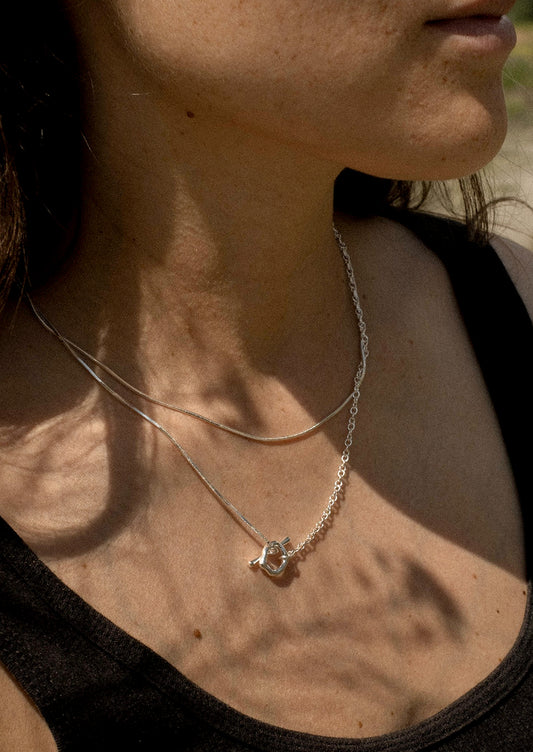 Close-up of a person wearing a delicate necklace with a small pendant.