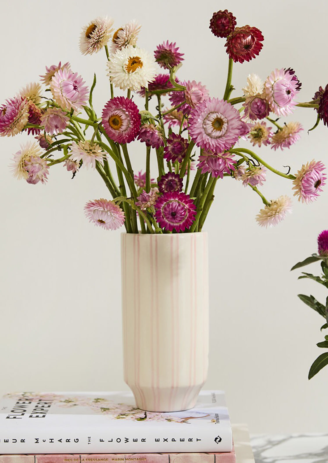 Vase with colorful flowers on a surface with books underneath
