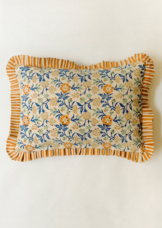 Floral patterned pillow with orange ruffle border on a white background