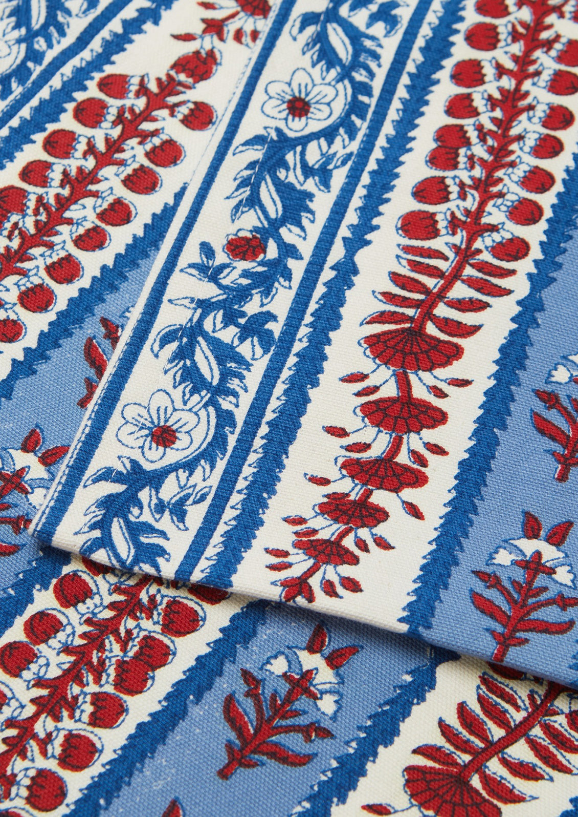 Decorative table runner with red and blue block printed floral pattern on a white background.