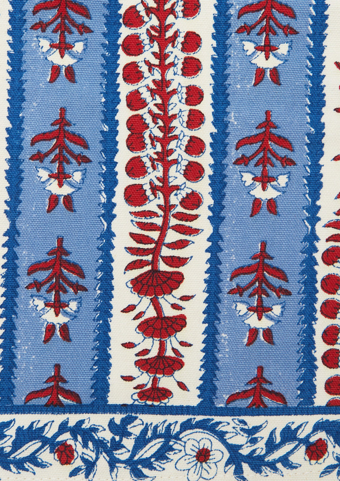 Decorative table runner with red and blue block printed floral pattern on a white background.