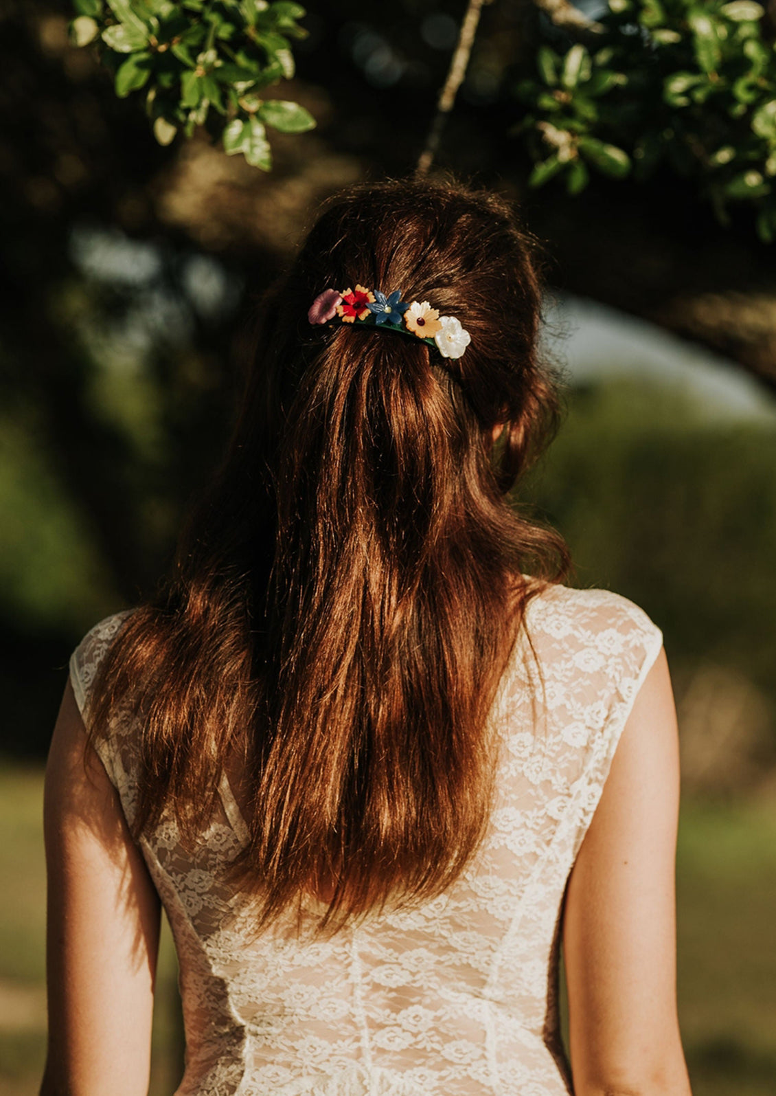 Person with long hair wearing a floral hair clip in a natural setting