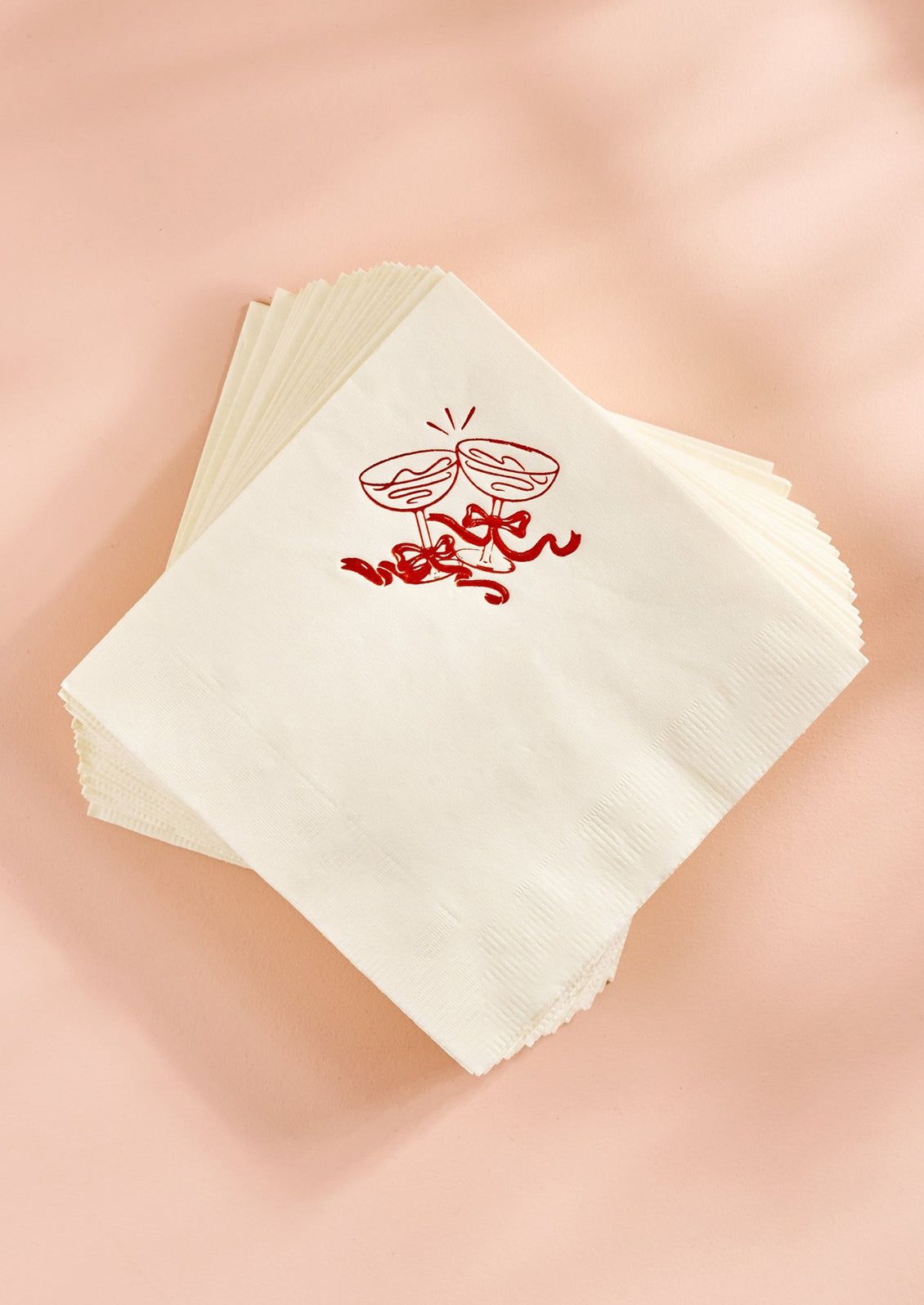 White paper napkins with red foil coupe glass graphic at corner.