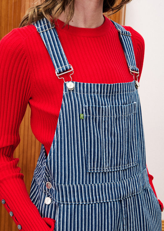 Person wearing a red sweater and blue striped overalls.