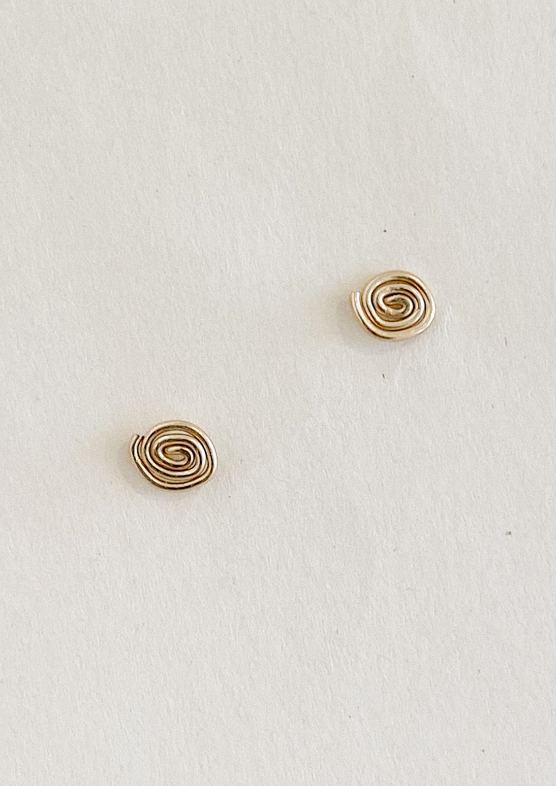 A pair of gold stud earrings with organic swirl shape.