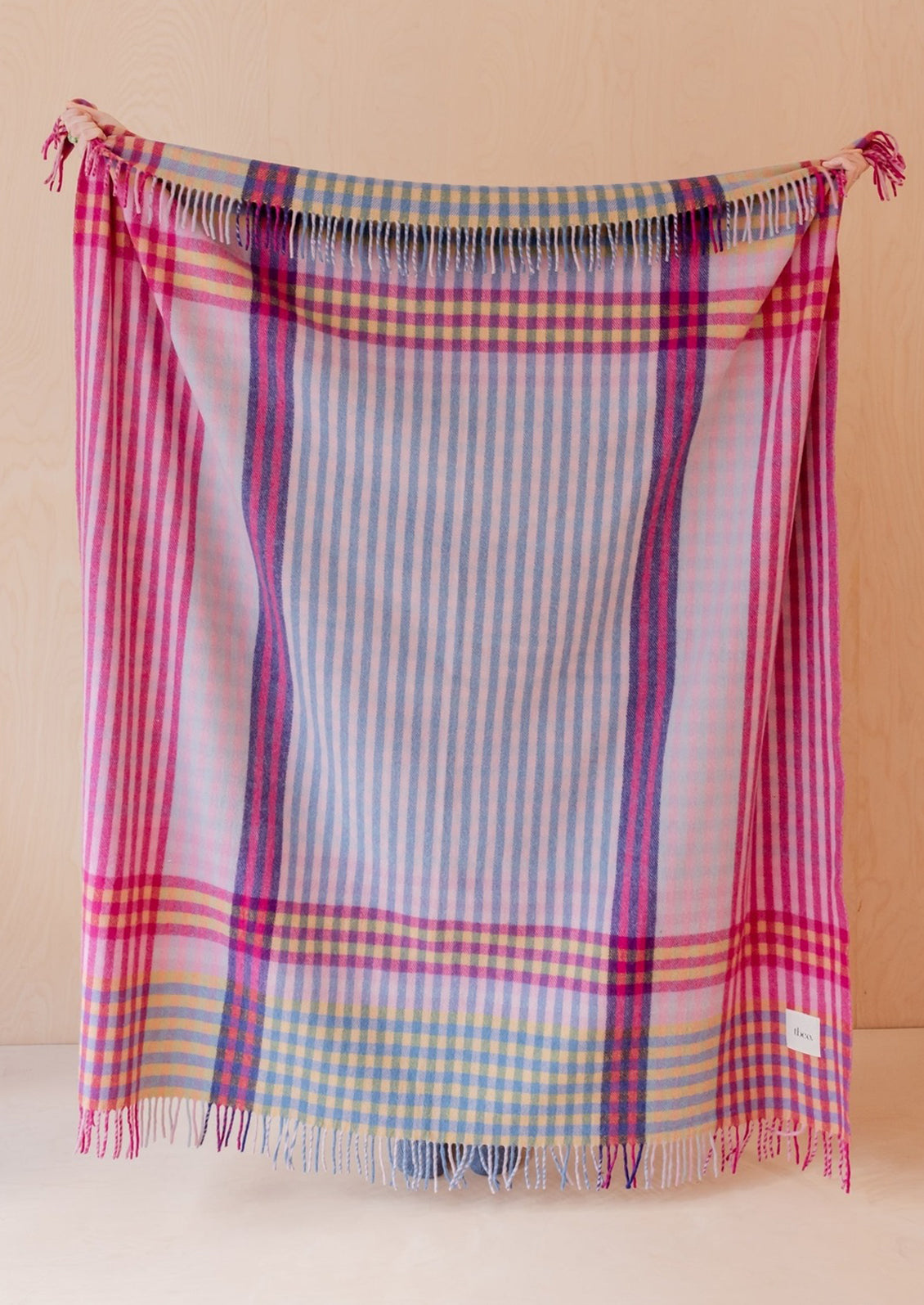 A colorful wool blanket with plaid pattern in pink, purple, yellow and blue hues.