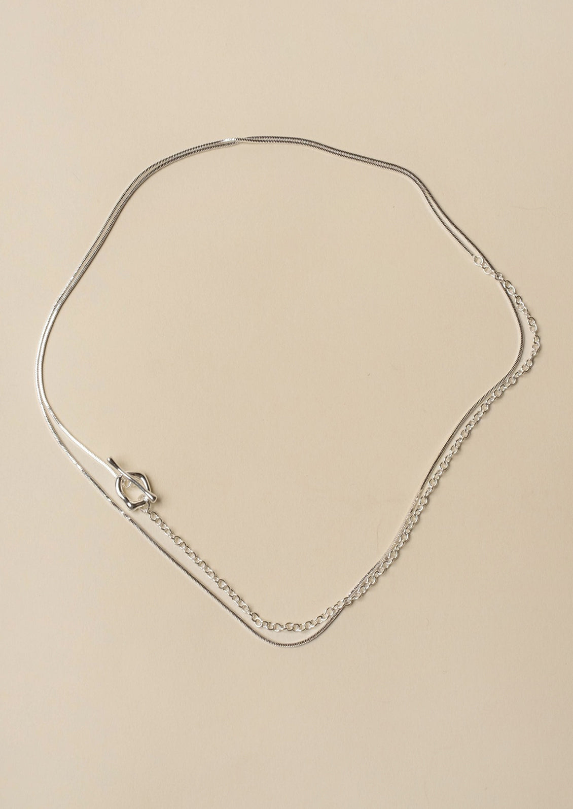 Silver necklace on a beige background