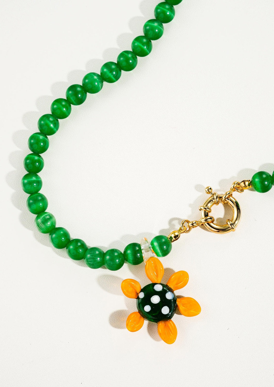 Green beaded bracelet with a sunflower charm on a white background