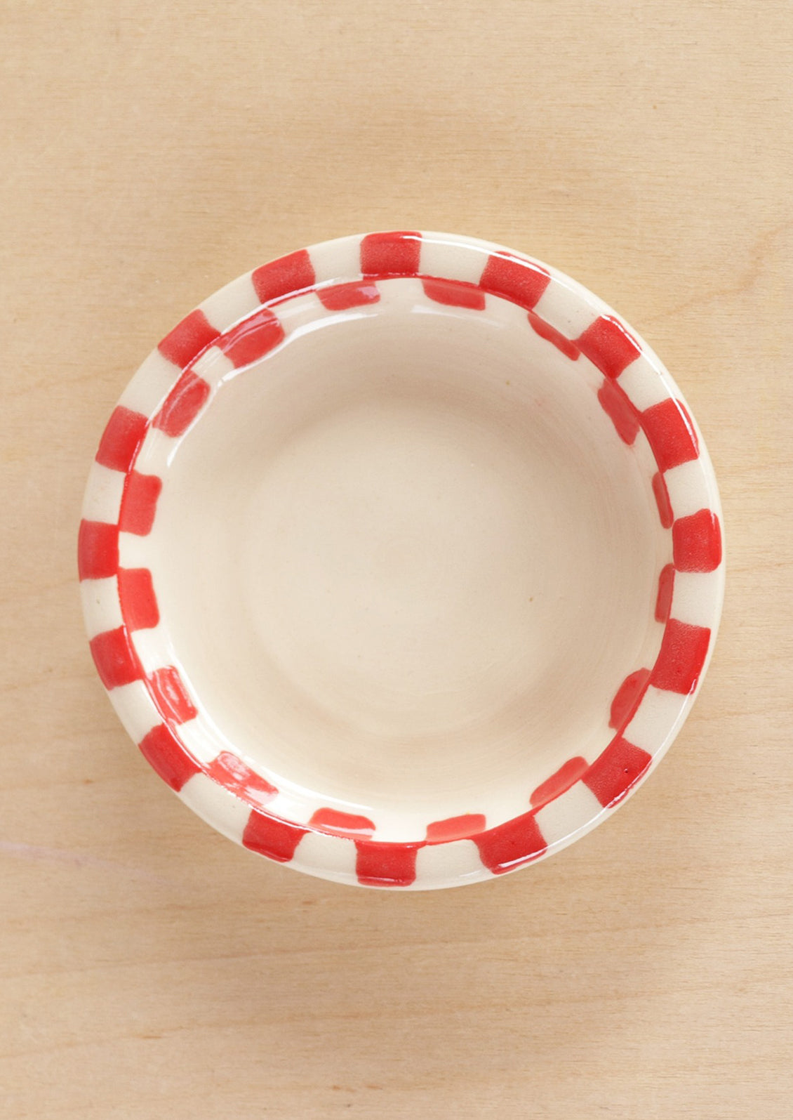 A round ceramic trinket dish with red checkered border.