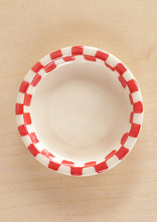 A round ceramic trinket dish with red checkered border.