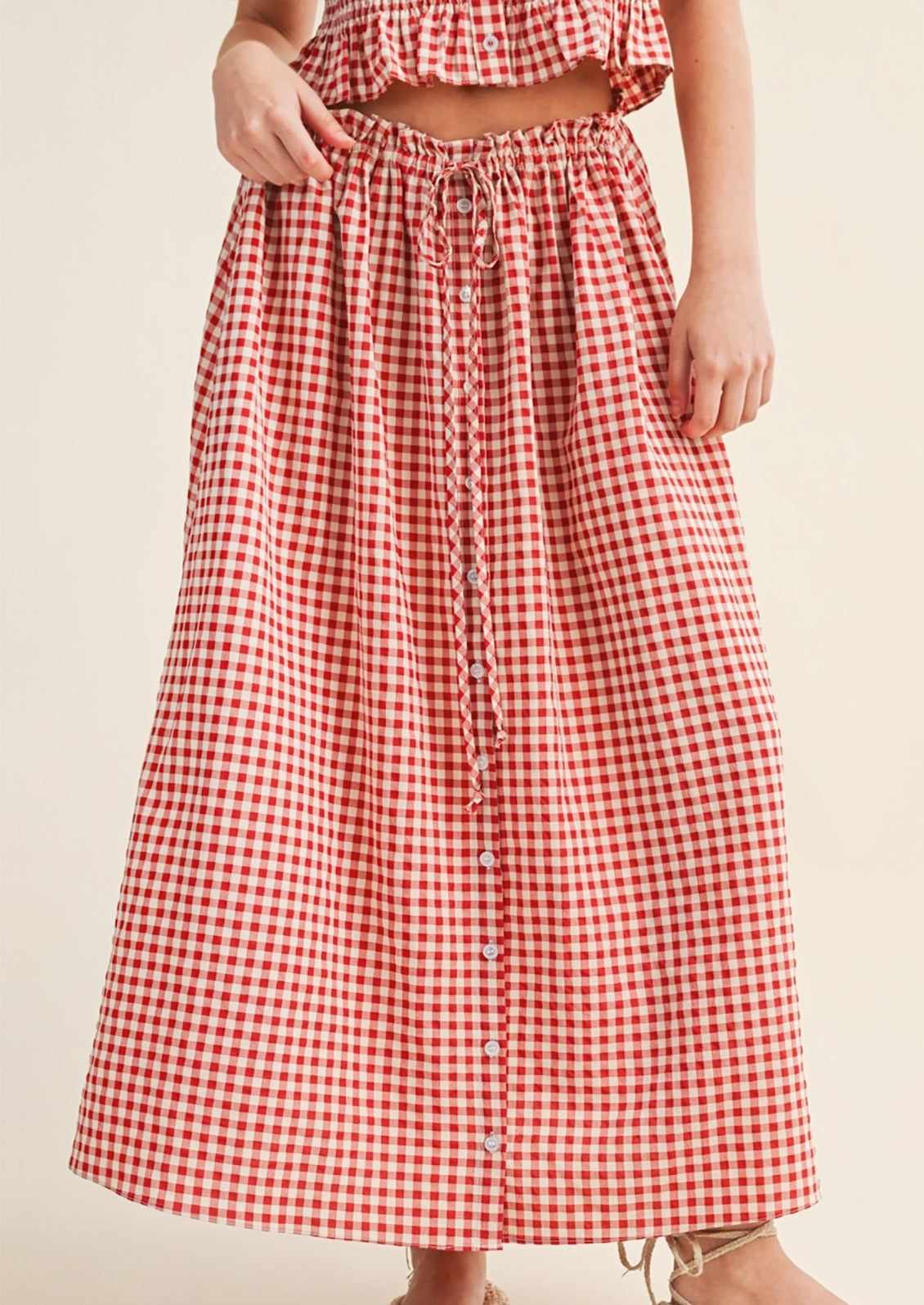 Red and white checkered skirt worn by a person on a beige background