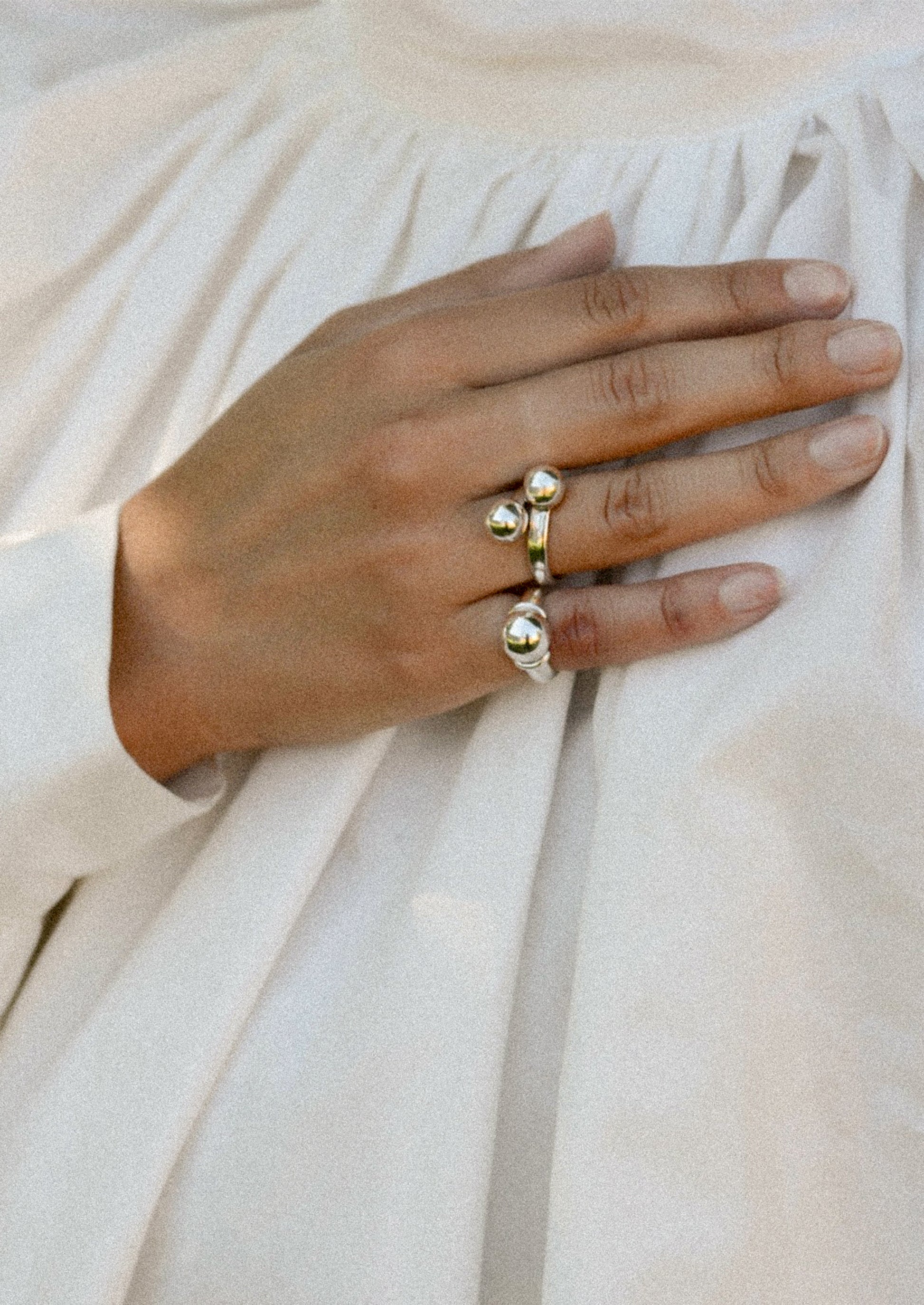 Hand wearing a gold ring on a light fabric background