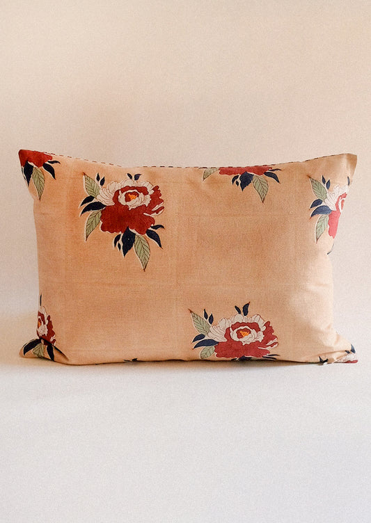 A lumbar throw pillow in cafe brown with red floral pattern.