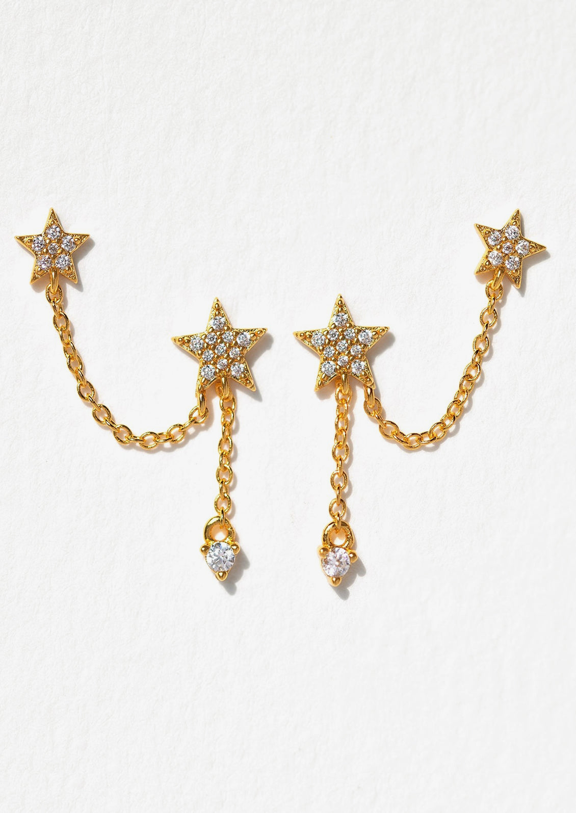 Gold star-shaped earrings with chain details on a white background