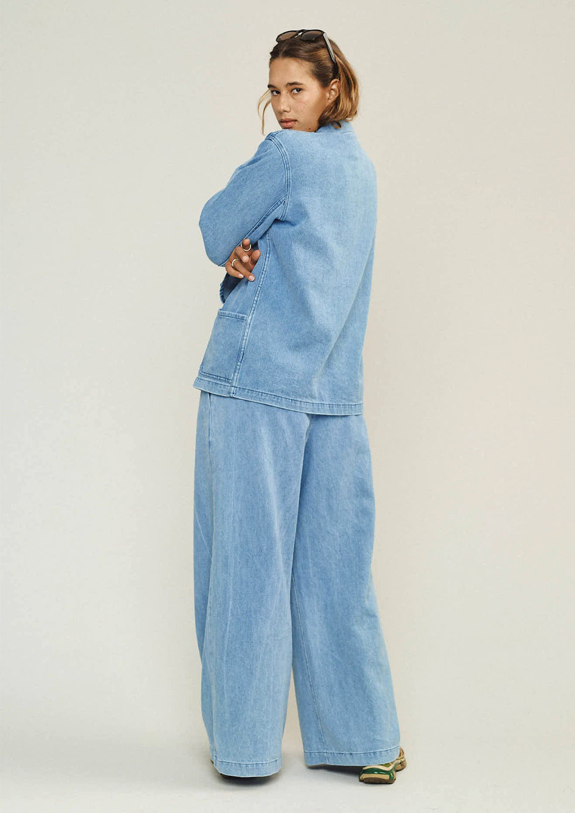 Person wearing a light blue denim outfit on a plain background