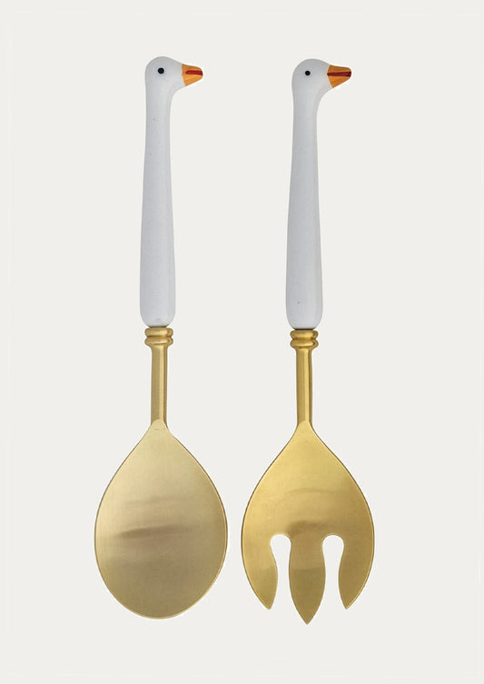 Two gold utensils with handles shaped like geese on a white background