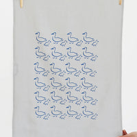 2: A grey linen tea towel with blue duck illustration print.