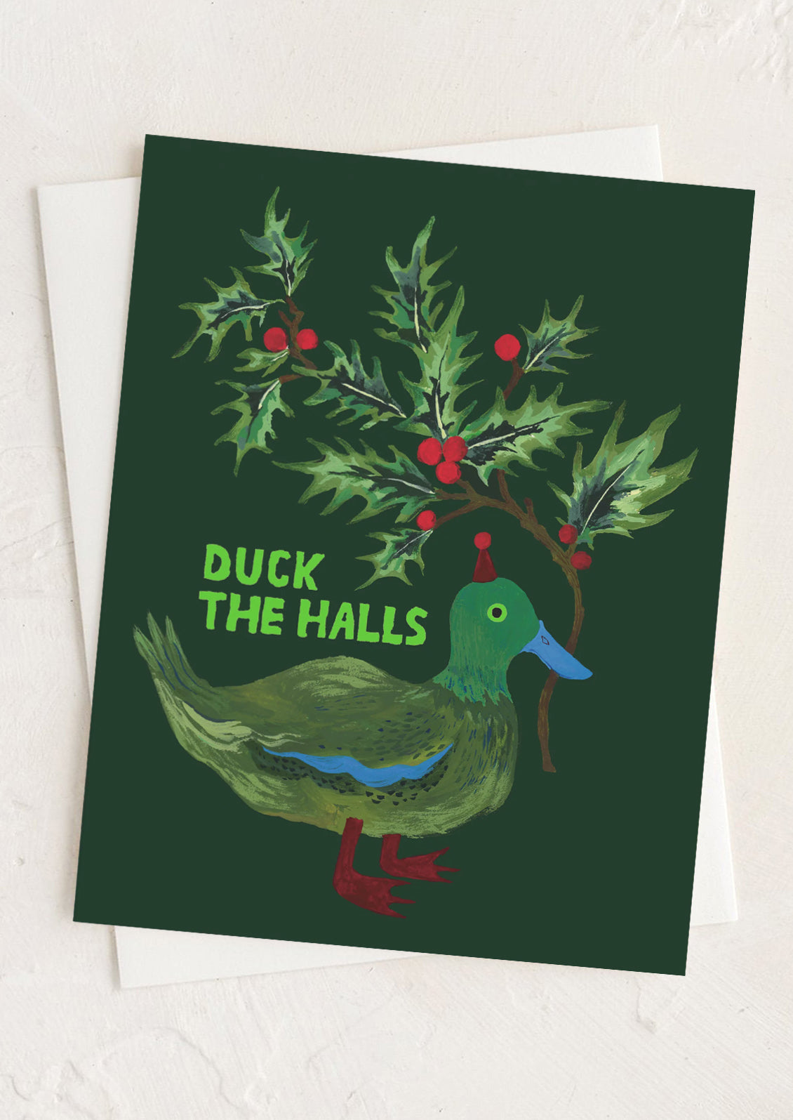 A greeting card with illustration of a duck holding a piece of holly, text reads "Duck the halls".