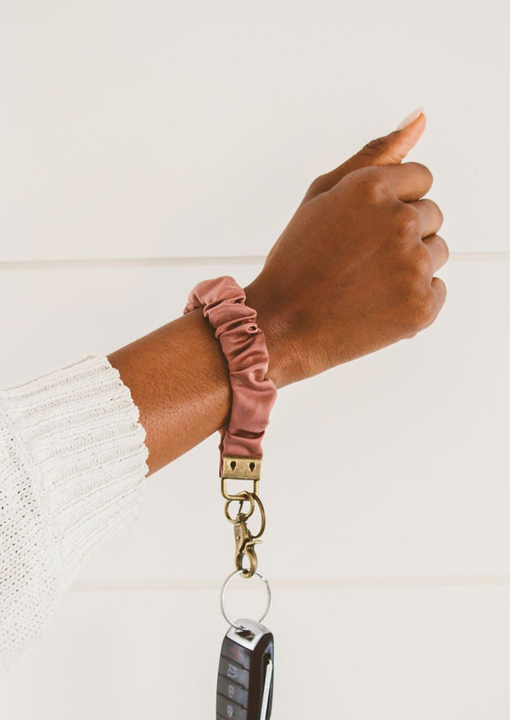 Dusty Rose: A dusty rose scrunchie wristlet keychain around a woman's wrist.
