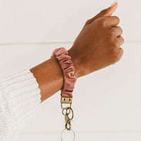 Dusty Rose: A dusty rose scrunchie wristlet keychain around a woman's wrist.