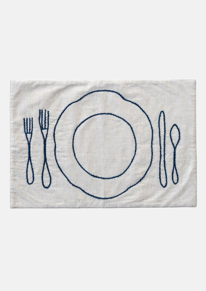 An off-white linen-cotton placemat with navy blue plate and silverware embroidery.